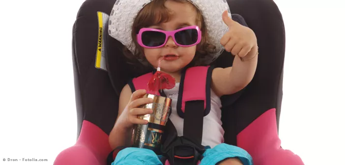 Kind mit Getränk und Sonnenbrille im Kindersitz
